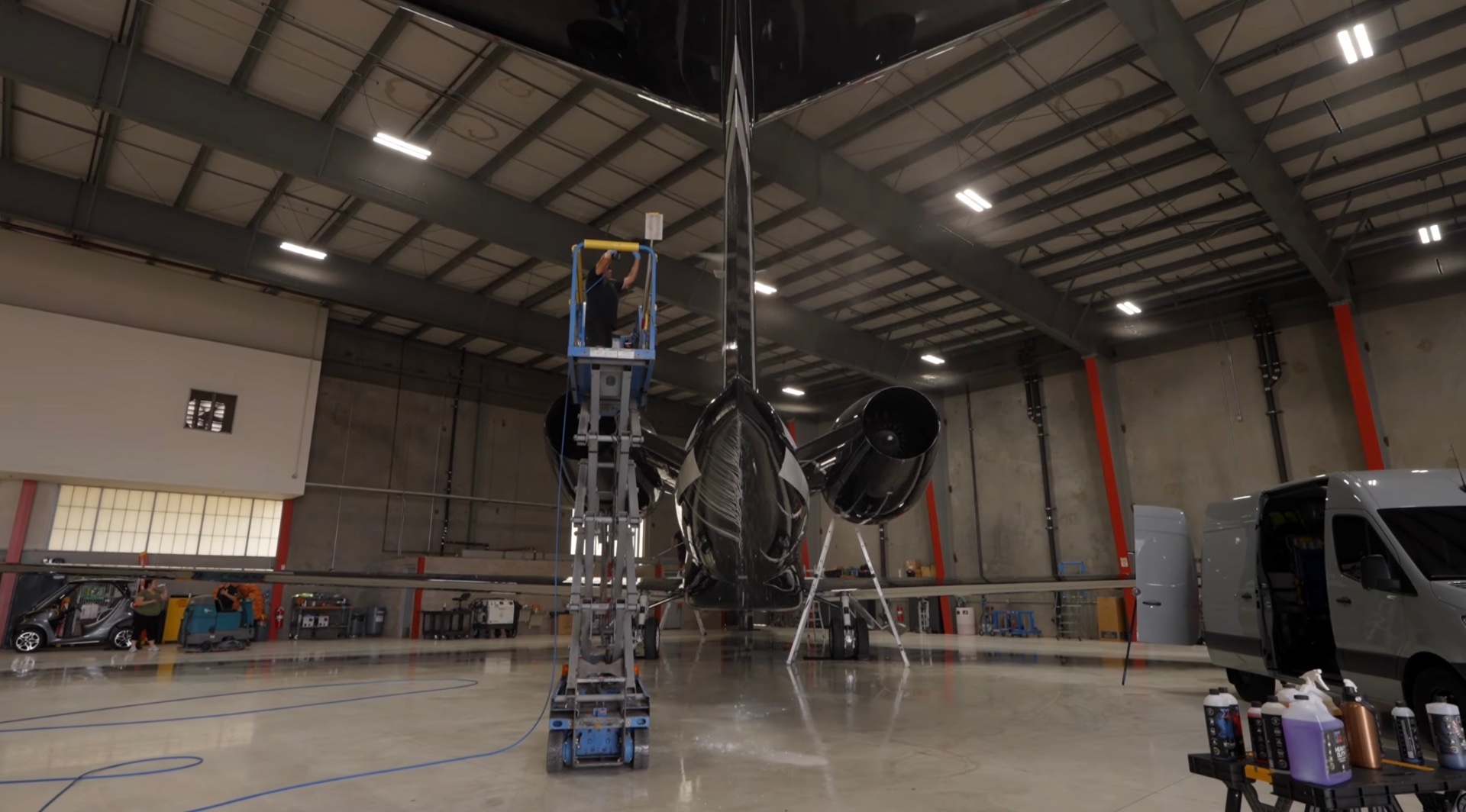 Aircraft appearance care in an Orlando hangar, technician on a lift detailing a private jet