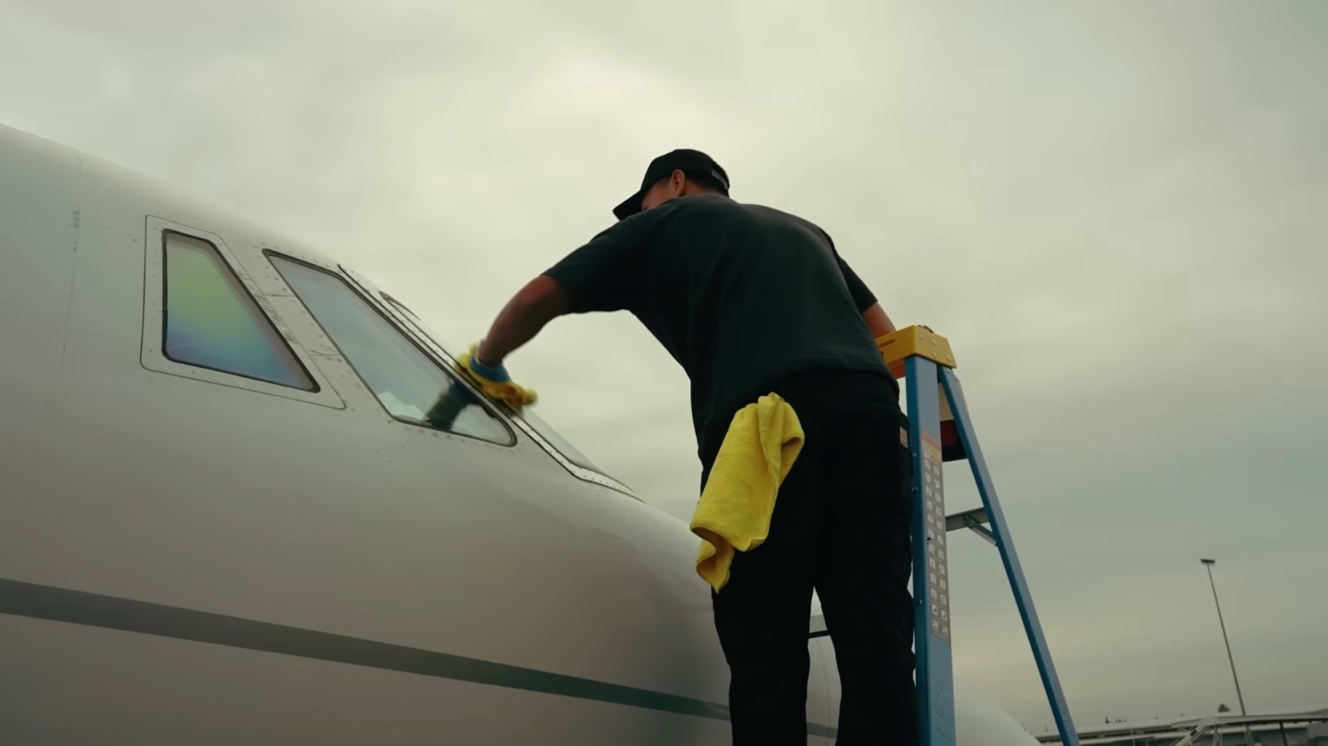 Technician hand-cleaning the cockpit windows of a private jet